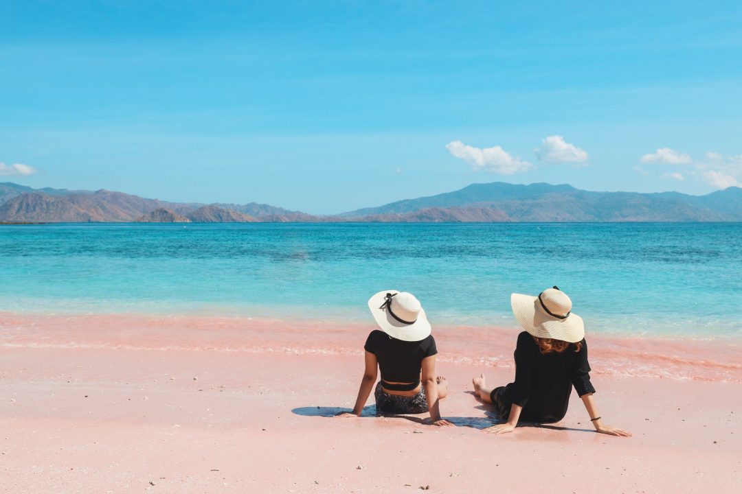 two-girls-with-summer-hat-sitting-on-beach.jpg